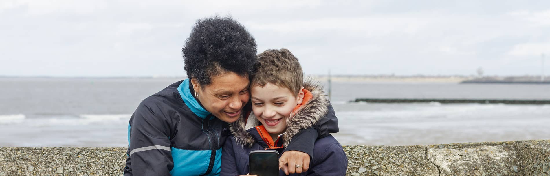 woman and teen boy looking at phone together 