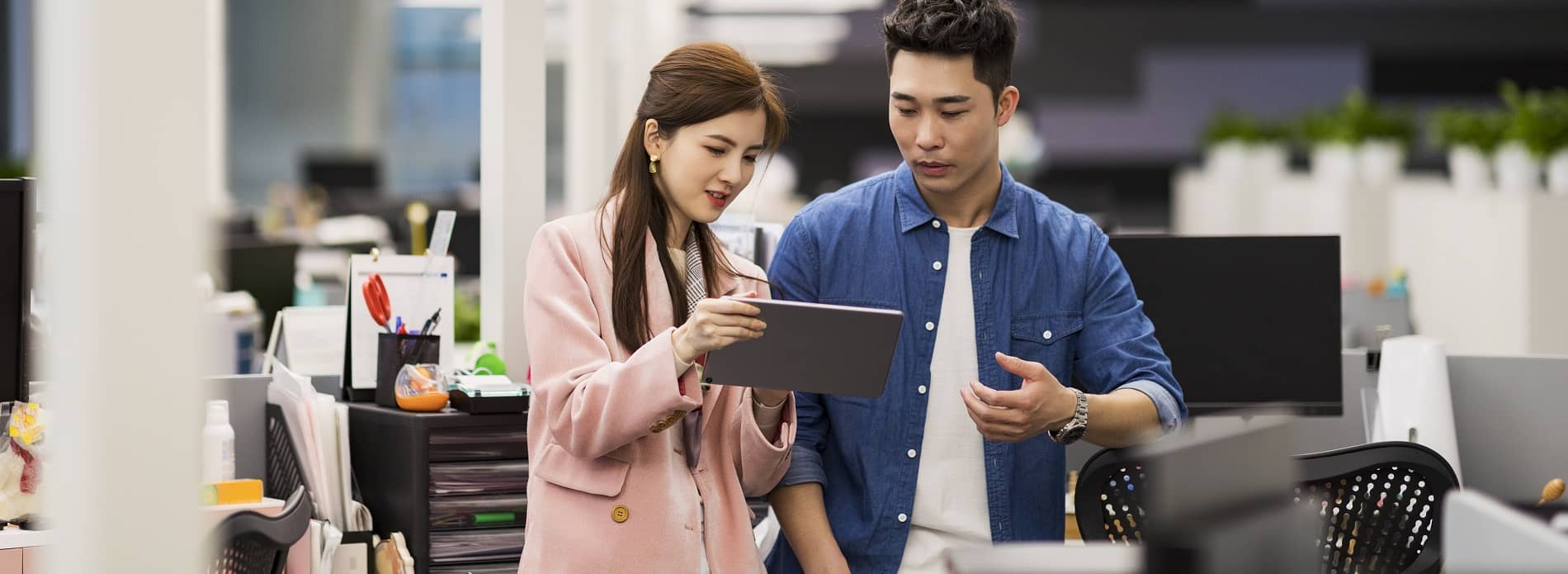 male and female colleague looking at iPad in office