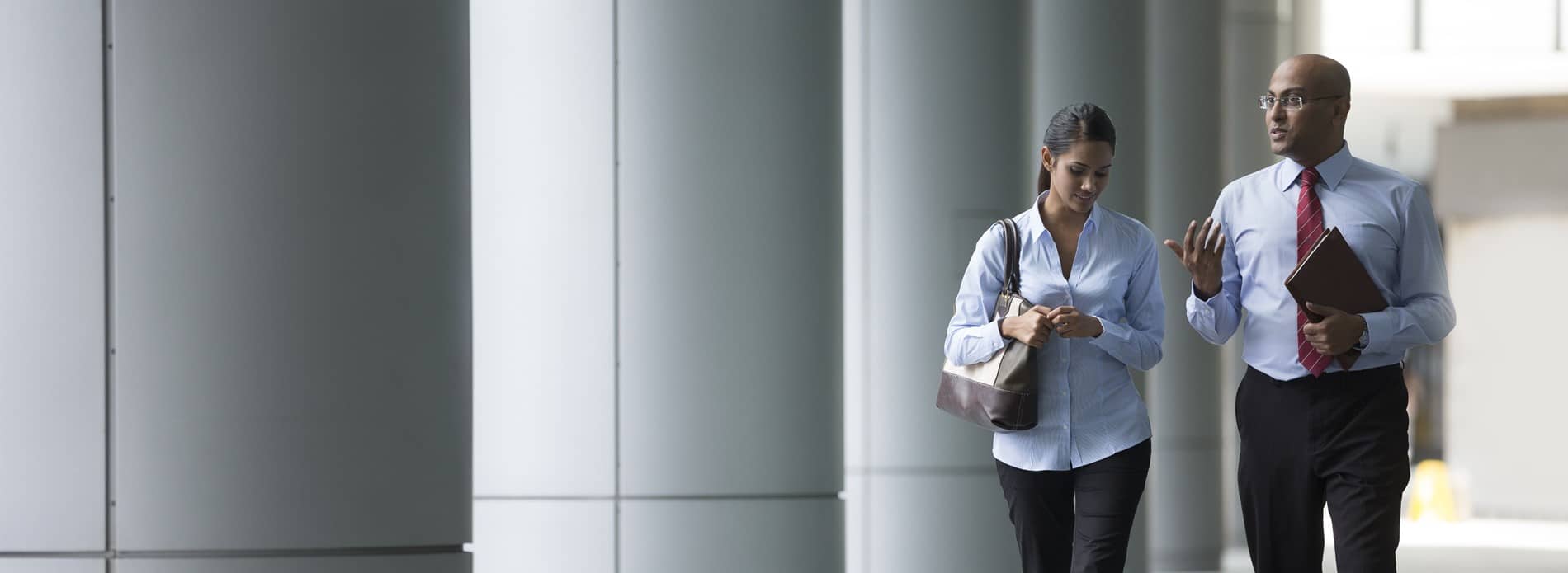 man and woman walking and talking through office corridor 