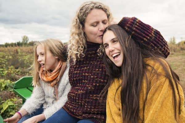 Mother with her daughters sitting on bench outside