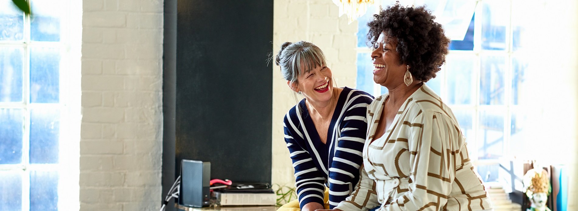 Two ladies sitting next to each other laughing
